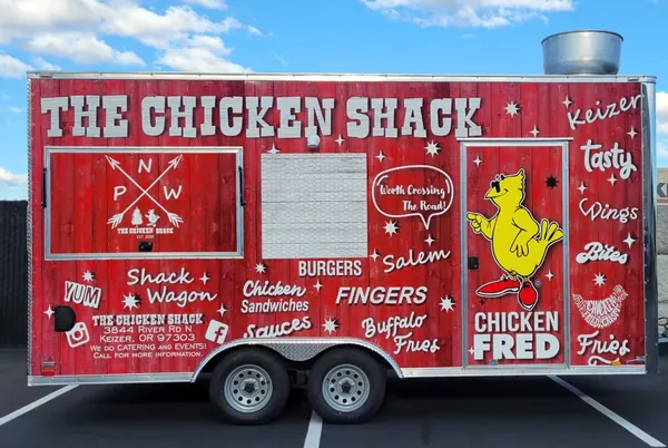 The Chicken Shack trailer: red barn-board sides with Chicken Fred and “Worth crossing the road”
